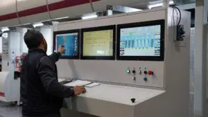 a man standing in front of a set of industrial monitors and pointing at the left-most rugged monitor.